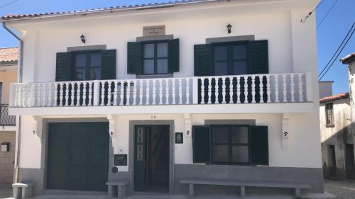 a white house with green shutters and a balcony at SPA - Casa do Avo BESELGA in Santo Amaro