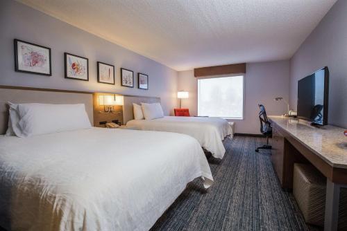 a hotel room with two beds and a flat screen tv at Hilton Garden Inn Atlanta Northpoint in Alpharetta