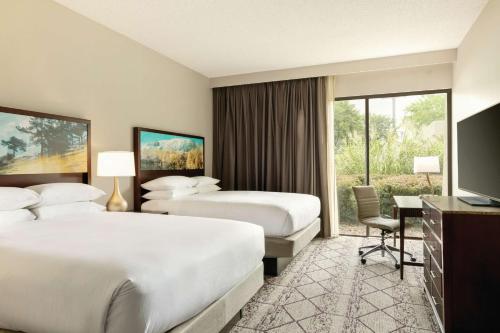 a hotel room with two beds and a desk at DoubleTree by Hilton Atlanta Northeast/Northlake in Atlanta