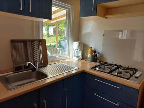 une cuisine avec évier et cuisinière ainsi qu'une fenêtre dans l'établissement Mobil-House Parc des Roches, à Saint-Chéron