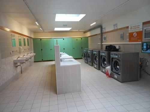 a laundry room with washing machines and green cabinets at Mobil-House Parc des Roches in Saint-Chéron