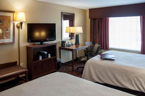 a hotel room with two beds and a flat screen tv at Hampton Inn & Suites Watertown in Watertown