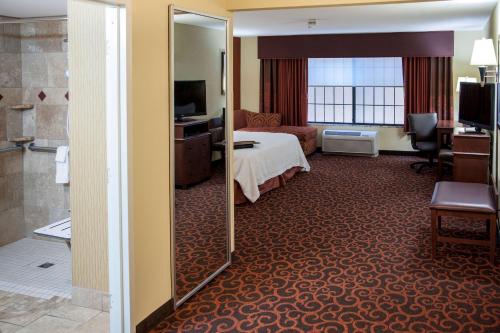 ウォータータウンにあるHampton Inn & Suites Watertownのベッドと鏡が備わるホテルルーム