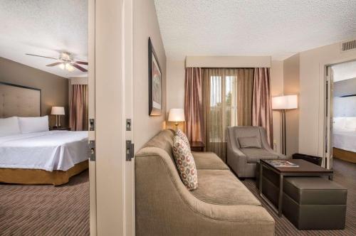 Homewood Suites by Hilton Austin South في أوستن: غرفه فندقيه بسرير واريكه وكرسي