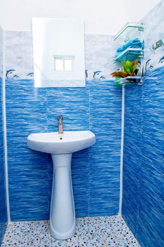 a bathroom with a sink and a blue tiled wall at PALM - 2minutes walk to the beach in Nungwi