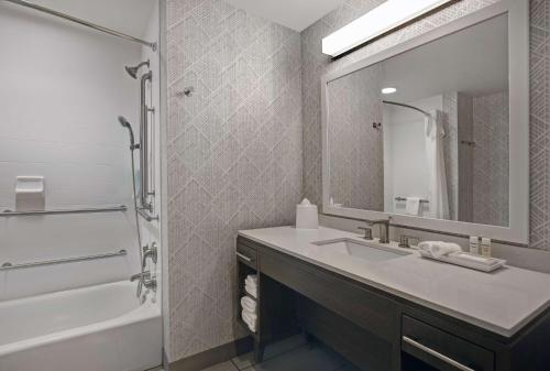 a bathroom with a sink and a tub and a mirror at Home2 Suites By Hilton Asheville Airport in Arden