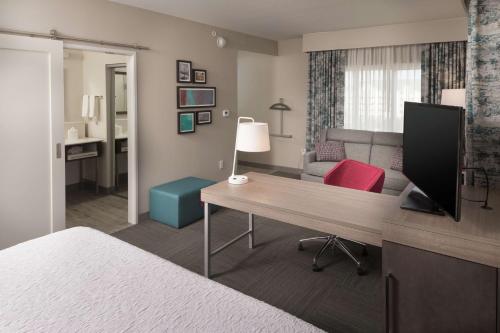 a hotel room with a desk and a bedroom at Hampton Inn & Suites Asheville Biltmore Area in Asheville
