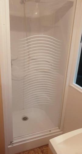 La salle de bains est pourvue d'une douche blanche et d'une fenêtre. dans l'établissement Ghislain et Pat, à Saint-Chéron