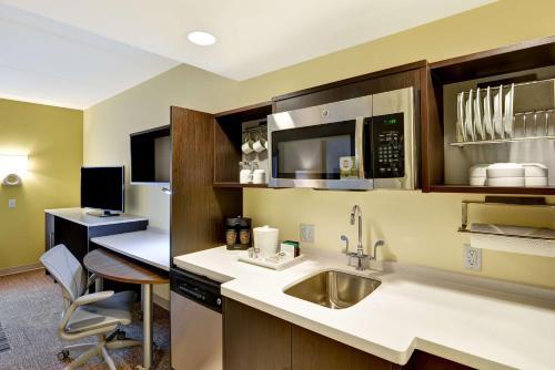 eine Küche mit einem Waschbecken und einem Schreibtisch mit einem Computer in der Unterkunft Home2 Suites By Hilton Dickson City Scranton in Dickson City