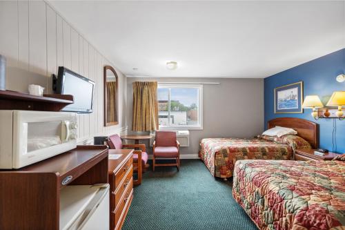 ロックランドにあるTrade Winds Innのベッド2台とテレビが備わるホテルルームです。