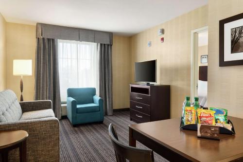 a hotel room with a couch and a chair and a table at Homewood Suites by Hilton Newtown - Langhorne, PA in Newtown