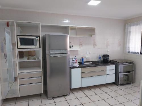 a kitchen with a refrigerator and a microwave at Ótimo Apartamento Guilhermina in Praia Grande