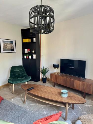 Il comprend un salon doté d'une télévision à écran plat et d'une chaise verte. dans l'établissement Le Perralieres charmant 2 chambres métro Flachet, à Villeurbanne