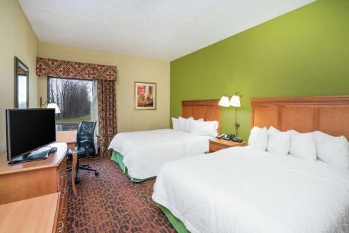 a hotel room with two beds and a flat screen tv at Hampton Inn Bardstown in Bardstown
