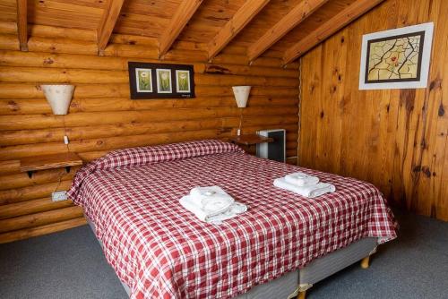 ein Schlafzimmer mit einem Bett in einer Holzhütte in der Unterkunft cabañas los Troncos in Junín de los Andes