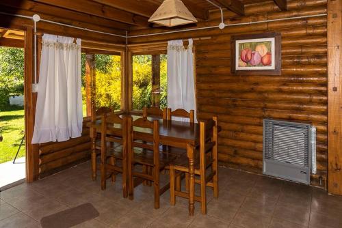 ein Esszimmer mit einem Tisch und Stühlen in einer Blockhütte in der Unterkunft cabañas los Troncos in Junín de los Andes