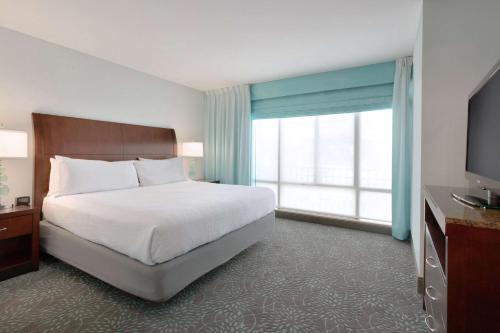 a hotel room with a bed and a large window at Hilton Garden Inn Worcester in Worcester