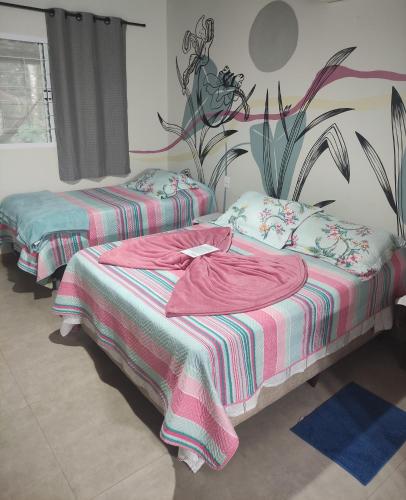 two beds in a room with pink and green sheets at Pousada Luz do Jamacá in Chapada dos Guimarães