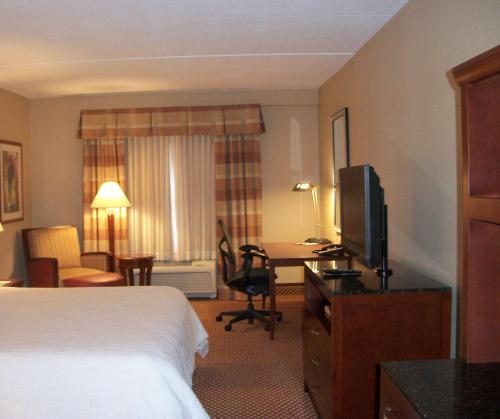 a hotel room with a bed and a desk with a television at Hilton Garden Inn Bangor in Bangor