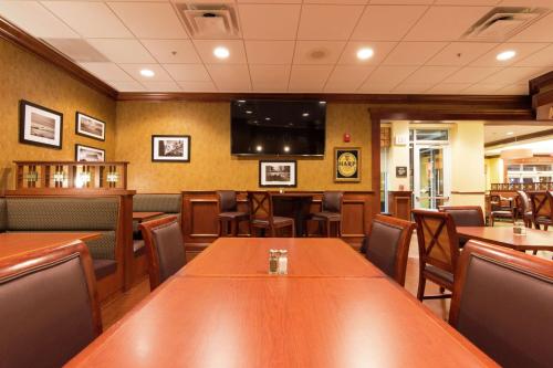 a restaurant with wooden tables and chairs and a flat screen tv at Hilton Garden Inn Bangor in Bangor