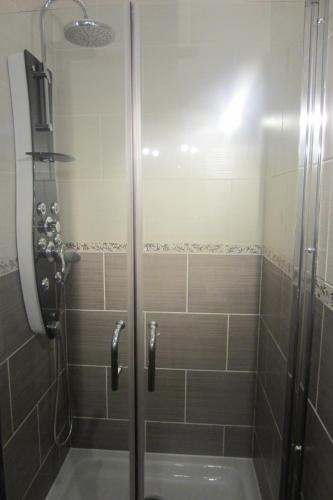 une douche avec une porte vitrée dans une salle de bain dans l'établissement Maison Au Milieu De La Foret, à Labastide-Rouairoux