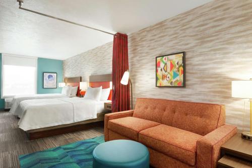Home2 Suites By Hilton Bismarck في بسمارك: غرفه فندقيه بسرير واريكه