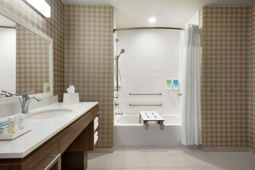een badkamer met een bad, een wastafel en een douche bij Home2 Suites By Hilton Bismarck in Bismarck