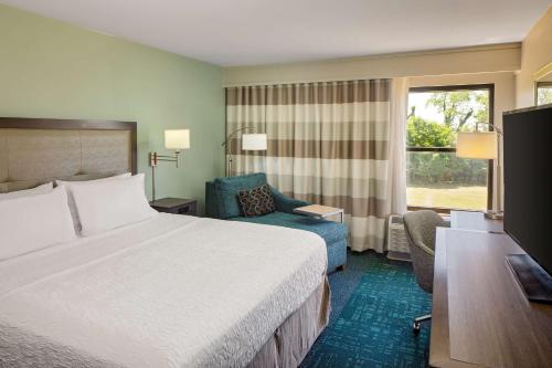 una camera d'albergo con un letto, una sedia e una finestra di Hampton Inn & Suites Nashville-Airport a Nashville