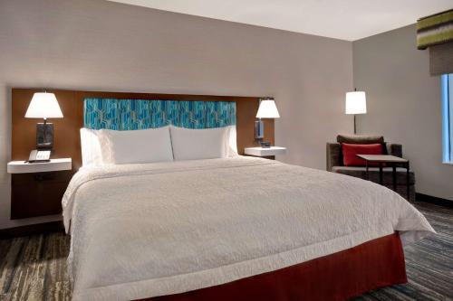 a hotel room with a large bed and a chair at Hampton Inn Pleasant View in Pleasant View