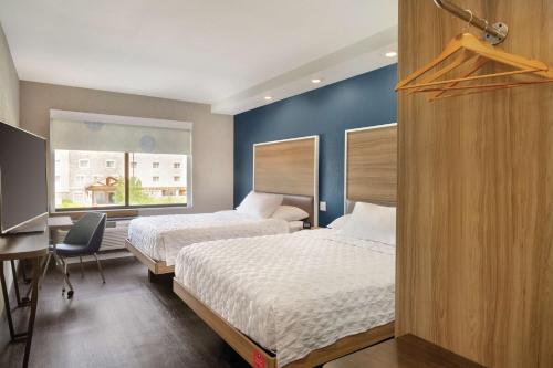 Cette chambre comprend deux lits, un bureau et une fenêtre. dans l'établissement Tru By Hilton Meridian Boise West Id, à Meridian