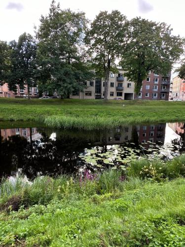 a pond in a field with a building in the background at Pråmkanalens Pensionat i Karlstad in Karlstad