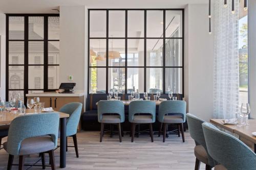 a dining room with tables and chairs and large windows at Hilton Garden Inn Boston Brookline, Ma in Brookline