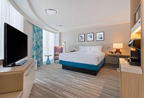 a hotel room with a bed and a flat screen tv at Hilton Garden Inn Boston Brookline, Ma in Brookline