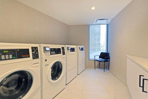 a laundry room with four washing machines and a chair at Hilton Garden Inn Boston Brookline, Ma in Brookline