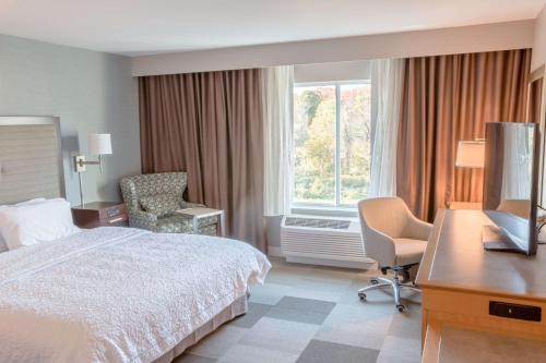 a hotel room with a bed and a desk and a television at Hampton Inn by Hilton Amesbury, MA in Amesbury