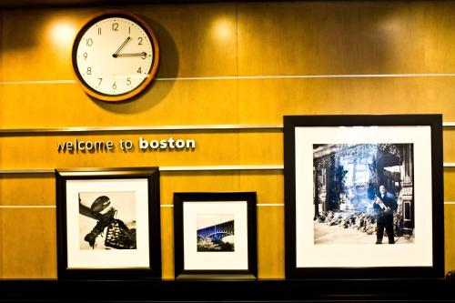 a clock on a wall with three framed pictures at Hampton Inn & Suites Boston Crosstown Center in Boston
