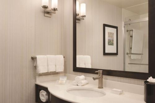 a bathroom with a sink and a mirror and towels at Hilton Garden Inn Boston Logan Airport in Boston