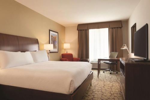 a hotel room with a bed and a desk and a television at Hilton Garden Inn Boston Logan Airport in Boston