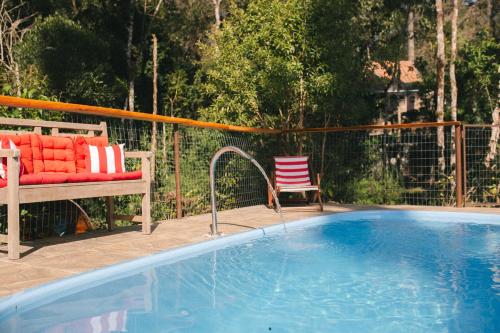 una piscina con un banco y una silla al lado en Recanto de Encantos, en Campos do Jordão