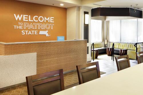 a waiting room with a welcome to the patroit state sign at Hampton Inn Boston-Natick in Natick