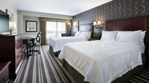 a hotel room with two beds and a television at Hampton Inn Boston-Natick in Natick