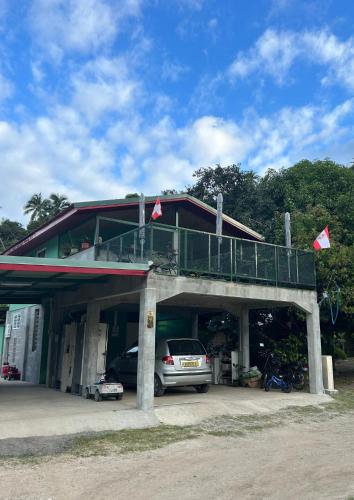 ein vor einem Gebäude mit Balkon geparktes Auto in der Unterkunft MOOZ LODGE, the local discovery in Afareaitu