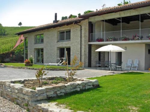 une maison avec une terrasse et un parasol dans la cour dans l'établissement Ca' Mia - Casa vacanze nelle vigne del Barolo, à Serralunga d'Alba