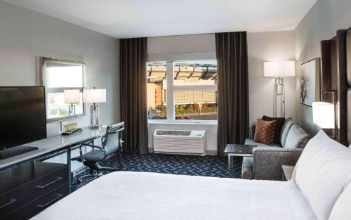 a hotel room with a bed and a desk and a window at Hilton Garden Inn Foxborough Patriot Place in Foxborough