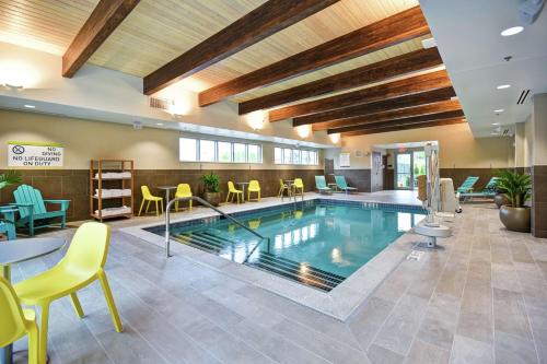 uma piscina no átrio do hotel com mesas e cadeiras em Home2 Suites By Hilton Walpole Foxborough em Foxborough
