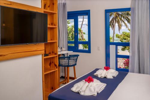 a bedroom with two beds and a flat screen tv at Vila Maria Pousada in Jericoacoara