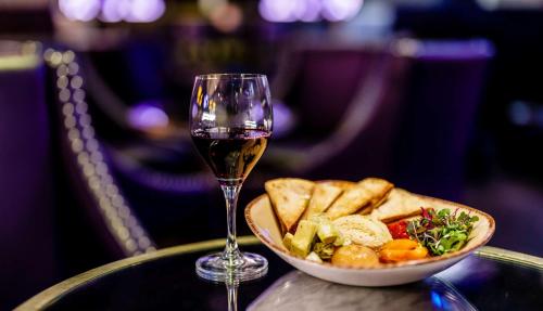 a glass of wine next to a bowl of food and a plate of bread at The Verve Boston Natick, Tapestry Collection by Hilton in Natick