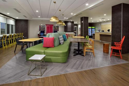 a living room with a green couch and tables and chairs at Home2 Suites By Hilton Beaumont, Tx in Beaumont