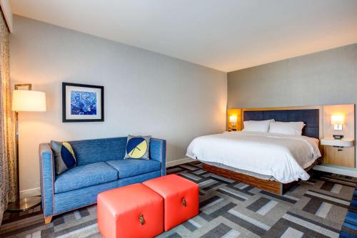 a hotel room with a bed and a blue couch at Hampton Inn & Suites Boston/Waltham in Waltham