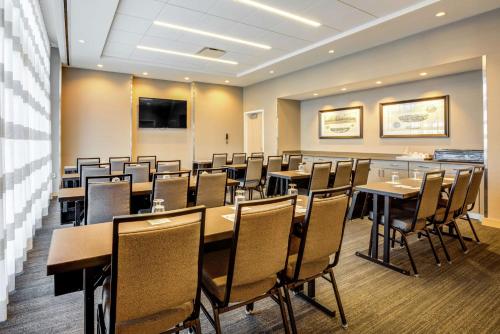 a conference room with tables and chairs and a screen at Hampton Inn & Suites Boston/Waltham in Waltham